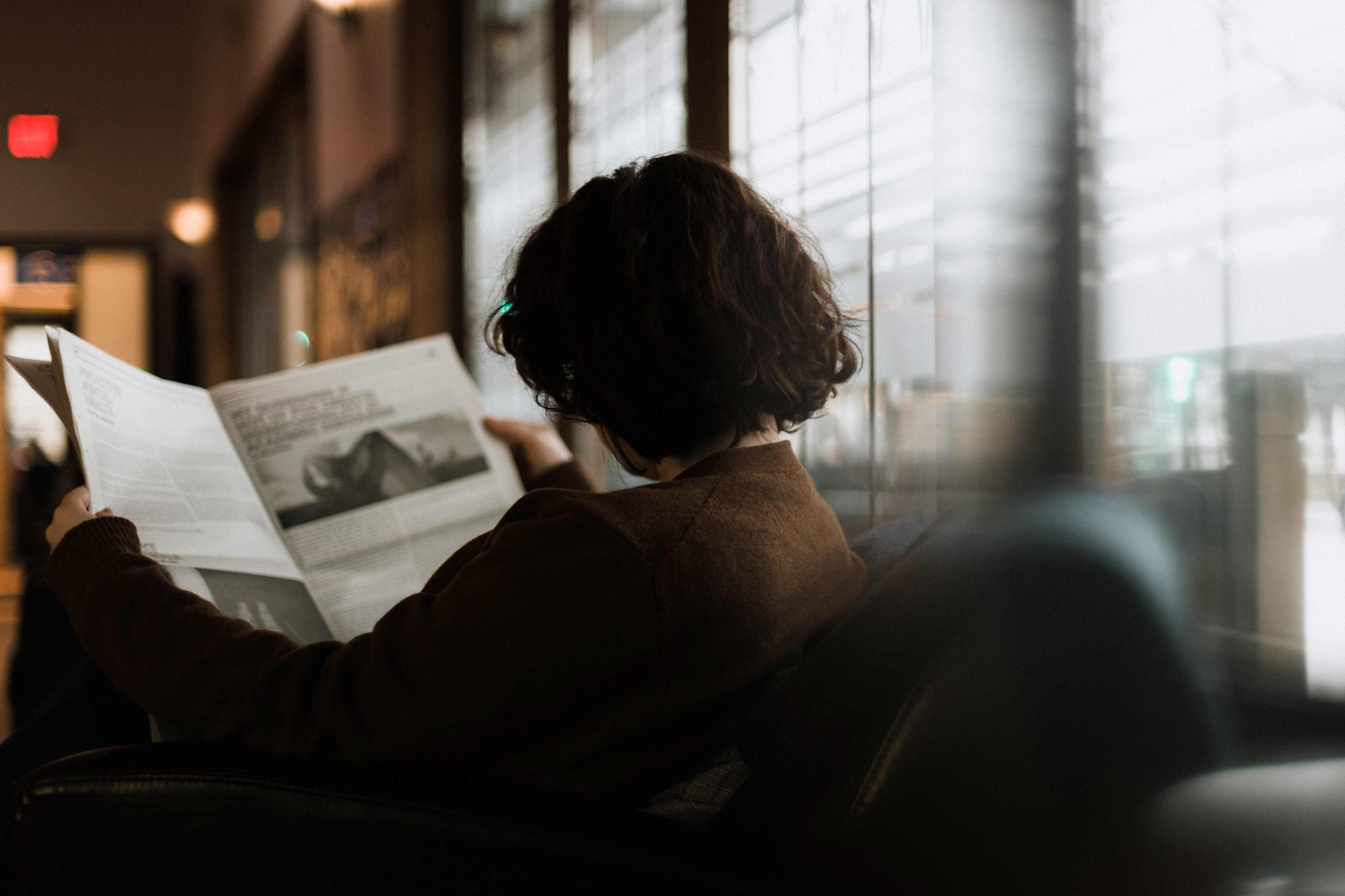 Lettura del giornale al bar (foto Priscilla Du Preez - Unsplash)