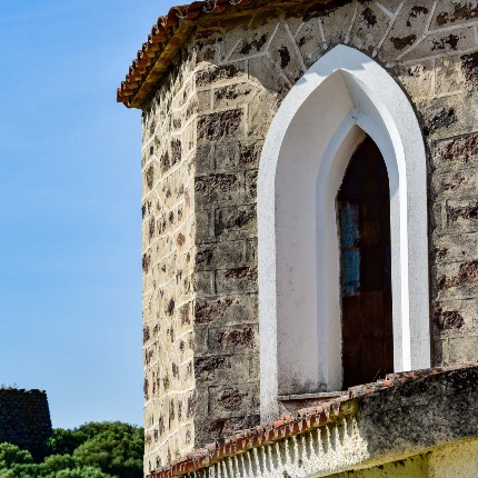 Santuario campestre della Madonna di Lucche. Scorcio dell'abside con il nuraghe sullo sfondo (foto Ivo Piras)