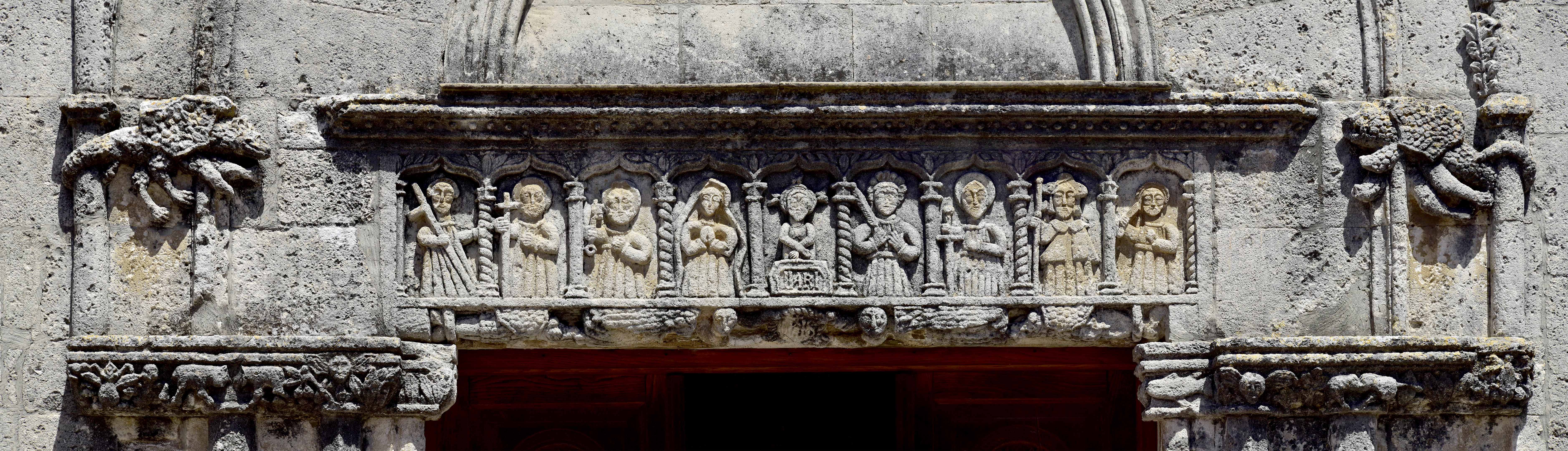 L'architrave del portale con il Cristo alla colonna, affiancato da una serie di santi, fra cui la Vergine, i Santi Pietro e Paolo, Santa Vittoria e San Giacomo, riconoscibile per la mantella e il cappello da pellegrino