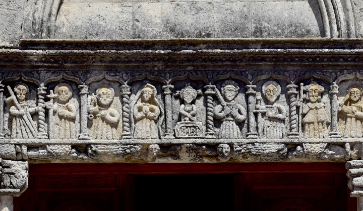 L'architrave del portale con il Cristo alla colonna, affiancato da una serie di santi, fra cui la Vergine, i Santi Pietro e Paolo, Santa Vittoria e San Giacomo, riconoscibile per la mantella e il cappello da pellegrino